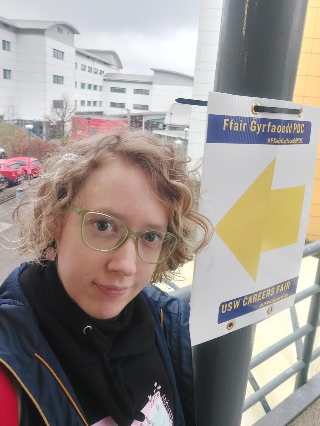 Shelley smiling at the camera next to a sign for the USW Careers Fair